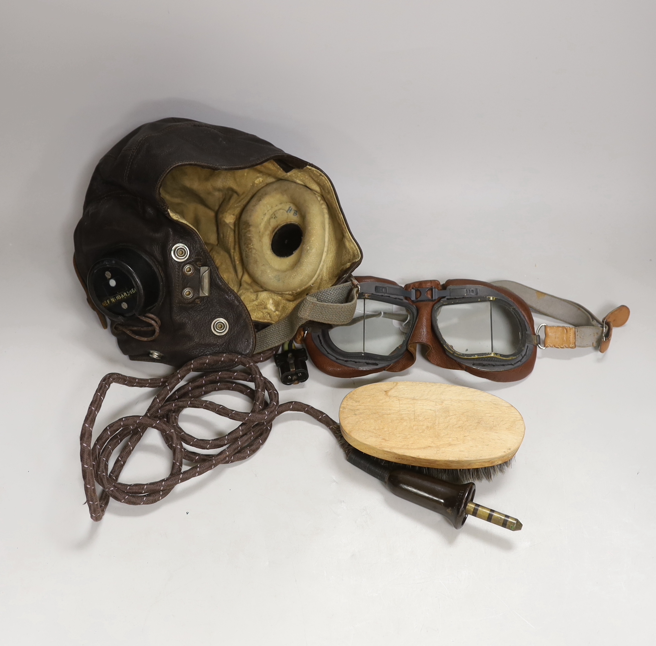 A WWII RAF flying helmet with speaker earpieces and original cables and plugs, Ref No.10A/13466, initialled in pen ‘HB’ for H. Brown 1320701, together with flying goggles and a contemporary clothes brush, provenance - by